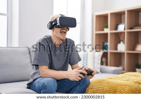 Young caucasian man playing video game using virtual reality glasses at home