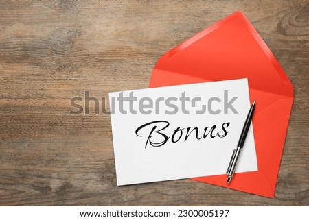 Red envelope, letter with word Bonus and pen on wooden table, top view. Space for text