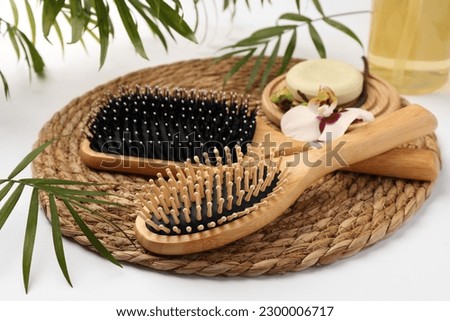 Wooden hairbrushes, solid shampoo, orchid flowers and leaves on white background Royalty-Free Stock Photo #2300006717