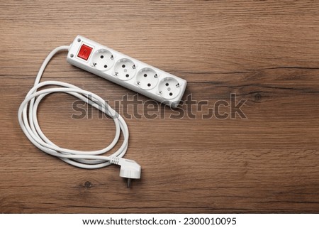 Power strip with extension cord on wooden floor, top view. Space for text Royalty-Free Stock Photo #2300010095