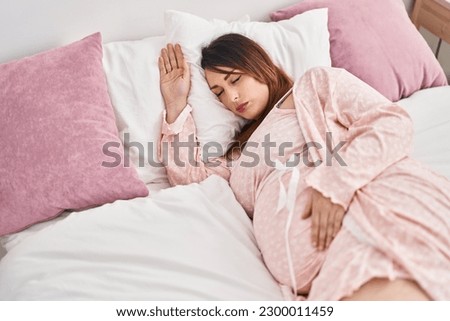 Young pregnant woman lying on bed sleeping at bedroom Royalty-Free Stock Photo #2300011459