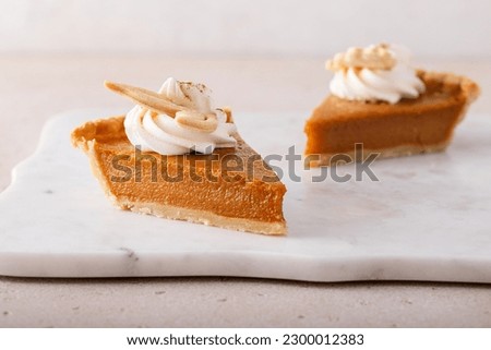 A slice of raditional pumpkin pie for Thanksgiving with whipped cream and leaf shaped decorations