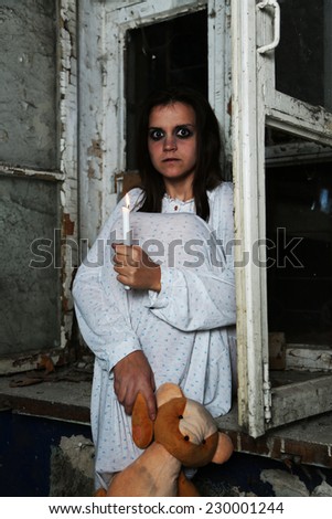 Horror Scene of woman sitting on windowsill and holding bear