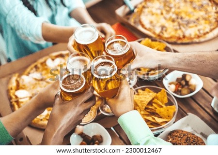 Close-up picture of people drinking beer and eating pizza on balcony at brewery pub table - Happy friends having dinner party at pizzeria restaurant - Dining lifestyle concept 