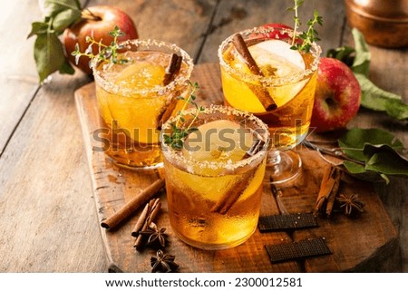 Apple cider margarita with brown sugar and spices on a rustic wooden surface, fall cocktail idea