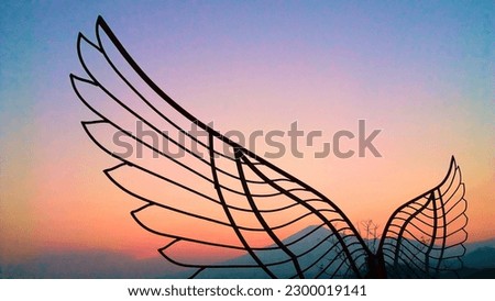 A wing sculpture at dusk with a beautiful mountain backdrop.