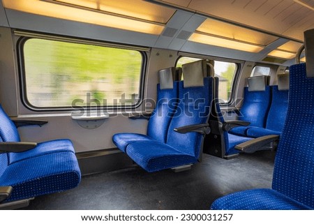 Passenger train with empty seats. Wide-angle long exposure, blurry green background out the window of an empty train in Switzerland, Europe, no people Royalty-Free Stock Photo #2300031257