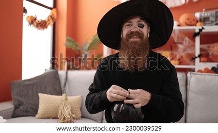 Young redhead man wearing wizard costume holding balloon at home