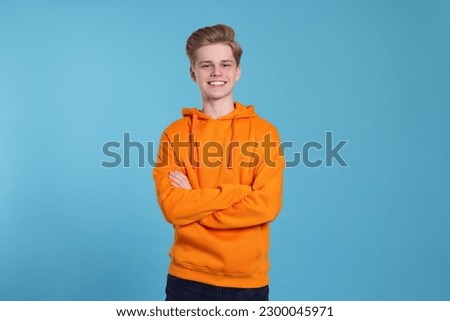 Portrait of smiling teenage boy on light blue background Royalty-Free Stock Photo #2300045971