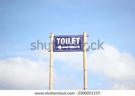 toilet sign with blue sky in the background.