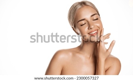 Skin care beauty. Young blond woman model moisturize clean skin without makeup, apply body face cream or serum on face, treating acne with cosmetology product, white background. Royalty-Free Stock Photo #2300057327