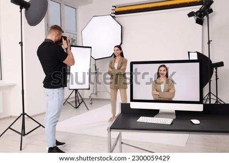 Professional photographer working with beautiful model in modern photo studio, selective focus