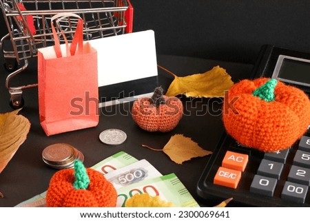 autumn sale layout on dark background, black friday, shopping basket next to coins and bills, orange pumpkins made of yarn and leaves, online shopping