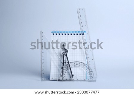 Triangle, notebook, protractor and compass on white background