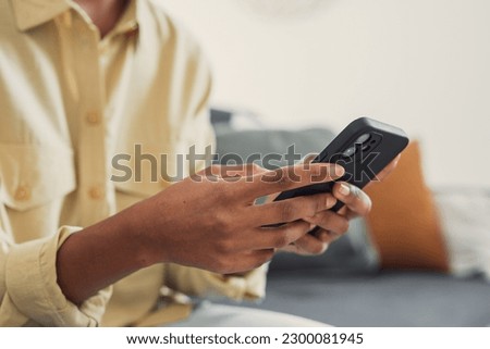 Hands of young dark skinned woman with finger rings using online app on mobile phone, making call, browsing Internet, chatting on social media, holding cellphone, texting, typing message. Close up