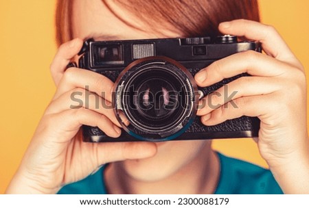 Cheerful smiling child holding a cameras. Little boy on a taking a photo using a vintage camera. Child in studio with professional camera. Boy using a cameras. Baby boy with camera.