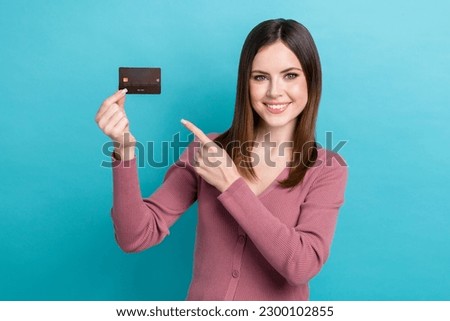 Photo of young charming girl wear pink shirt hold card point finger enjoy non limit shopping advert isolated on aquamarine color background