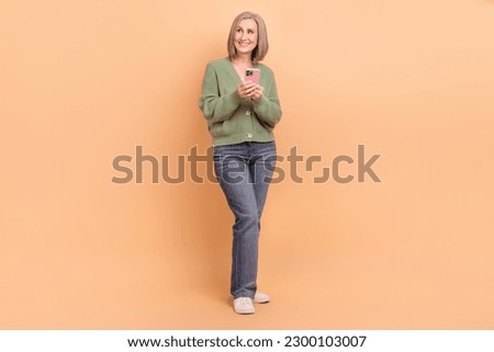 Full size photo of cheerful person wear knit pullover denim trousers hold smartphone look empty space isolated on pastel color background