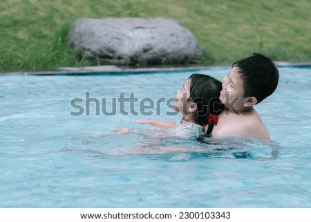 Two Southeast Asian children playing in the water at a swimming pool. Soft focus or unfocused.