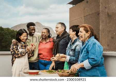 Multi generational friends having fun cooking together at house rooftop - Summer gatherings and food concept Royalty-Free Stock Photo #2300108921