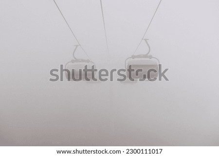Amusement park rides, excursion with ski lift in the fog. Natural park background, abstract scenic landscape in mountains. Vacation trip ideas Royalty-Free Stock Photo #2300111017