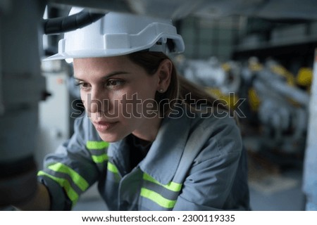 Female Technician Inspecting and repairing robotics arm in robots hangar and test the operation of the machine after being used for a while, as well as updating the software and calibration Royalty-Free Stock Photo #2300119335