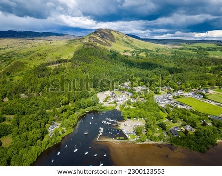 Aerial viewof a conical shaped hill overlooking a small village (Balmaha, Loch Lomond, Scotland) Royalty-Free Stock Photo #2300123553