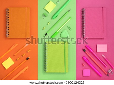 Flatlay knolling comosition of bright orange, green and pink stationery.