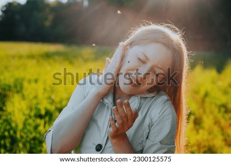 Young woman tries to kill a mosquito on her cheek Royalty-Free Stock Photo #2300125575