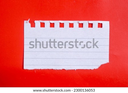 Ripped lined notebook paper on red background with copy space. Royalty-Free Stock Photo #2300136053