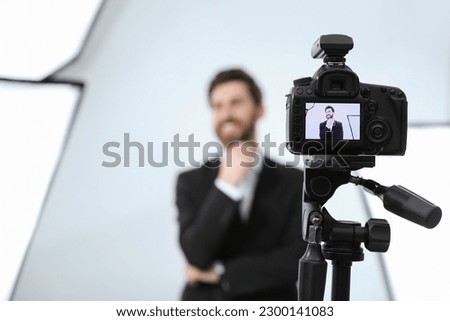 Handsome happy model posing for camera in modern studio, selective focus. Professional photo session