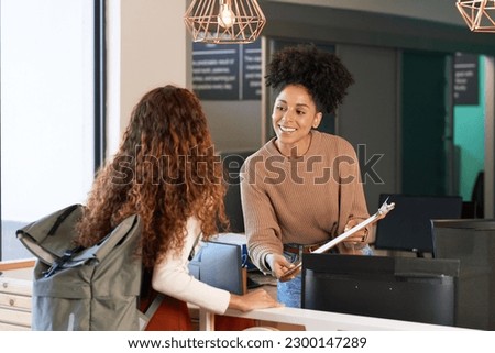 Young woman checks in at front desk, reception, hotel, college library admission Royalty-Free Stock Photo #2300147289