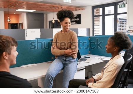 Three diverse young colleagues have an informal meeting, bright open plan office Royalty-Free Stock Photo #2300147309
