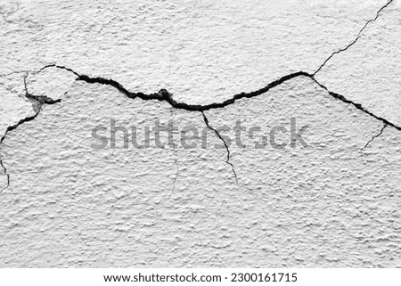 Big winding horizontal crack on old white plastering wall. Copy space. Selective focus. Royalty-Free Stock Photo #2300161715