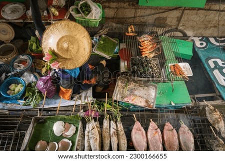 Woman selling fresh food at floating food market near Hua Hin, Thailand. South East Asia travel. Royalty-Free Stock Photo #2300166655