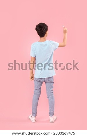 Little boy drawing with chalk piece on pink background, back view. Children's Day celebration Royalty-Free Stock Photo #2300169475