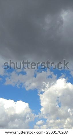 weather when there are black clouds and white clouds meet in a clear blue sky.