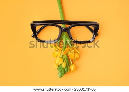 Stylish eyeglasses and flower on yellow background