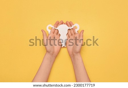 Woman with paper uterus on yellow background. Hormones concept