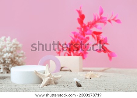 Decorative plaster podiums, coral, seaweed and starfish in sand on pink background Royalty-Free Stock Photo #2300178719