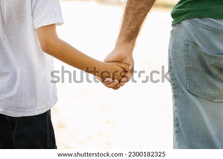 Old caucasian grandfather hold hand of little mixed race boy, enjoy free time, walk outdoor on white background, sun flare. Fun in park together, family relationship, weekend and vacation Royalty-Free Stock Photo #2300182325