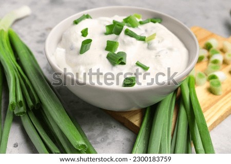 Bowl of tasty sour cream with green onion on table Royalty-Free Stock Photo #2300183759