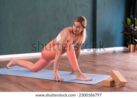 Yoga pose for health and body flexibility blonde woman doing effective exercise on blue mat laid on wooden floor professional yoga training in cozy studio