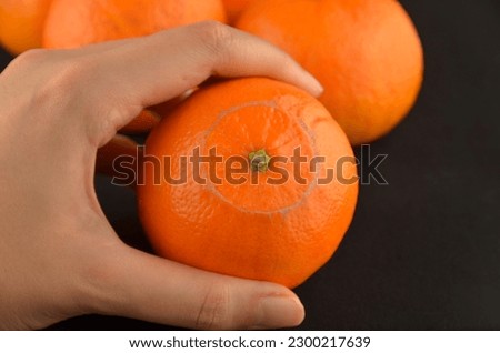 A tangerine in a hand on a black background