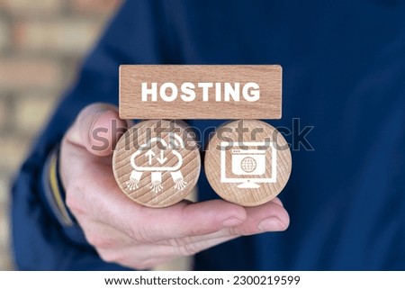 Concept of web hosting, domains name registration, internet technology. Man holding wooden blocks with icons and word: HOSTING. Internet database. Royalty-Free Stock Photo #2300219599