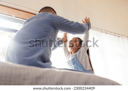 little Asian girl screams and plays with her dad in her hands, Korean child gives five to her father at home, man educates and plays with her daughter in the room