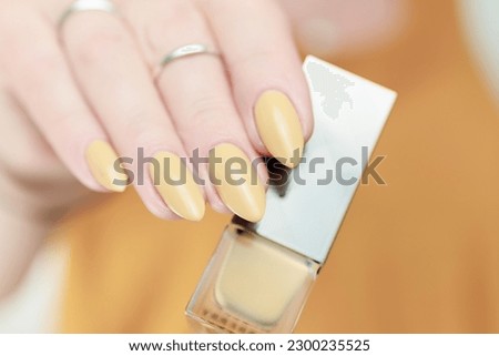 Female hand with long nails and a pale yellow manicure 