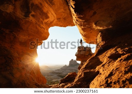 Horizontal image woman standing at dramatic viewpoint at Merry-go-round Rock in Sedona Arizona at sunset with sun flare admiring the landscape view. Royalty-Free Stock Photo #2300237161