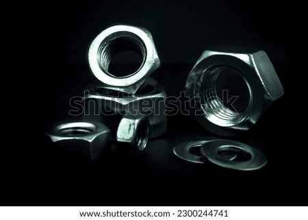 Metallic nuts and washers. Low-key concept picture taken in studio with soft-box and dark background representing some mechanical components.