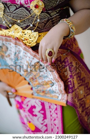 close-up photo of Asian woman wearing Balinese traditional dress name Payas Alit. fans, ring bracelets and Balinese batik sarongs